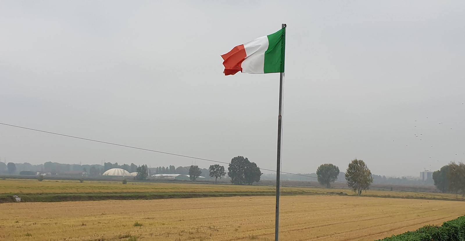 Bandiera italiana che sventola nelle campagne lombarde